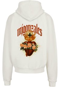 Hvid hættetrøje med et grafisk design af et hjerte med flammer, roser og dekorative detaljer, med teksten "migonztales" ovenfor.
