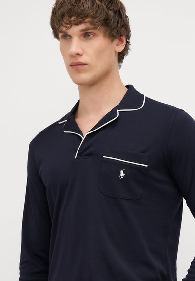 Jūras spēku garām piedurknēm polo krekls ar baltu apdari, kabatu un mazu izšūtu logotipu uz krūtīm. Mīksts audums un brīvs piegriezums.