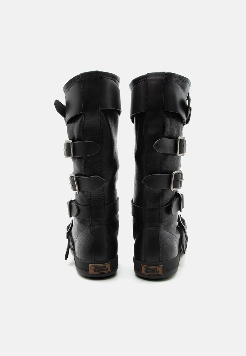 Coppia di stivali alti in pelle nera con tre cinturini con fibbie sul retro e una piccola etichetta marrone vicino alla suola.