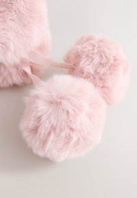 Zwei weiche, flauschige hellrosa Pompons, die durch ein dünnes rosa Band auf einer weißen Oberfläche verbunden sind.