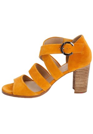 Yellow suede heel sandal with three wide straps and an ankle buckle. Features a textured stacked heel for added grip and stability.