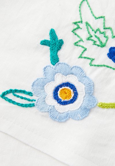 Tessuto ricamato con un fiore azzurro chiaro con centro giallo, petali bianchi e foglie verdi su uno sfondo bianco.