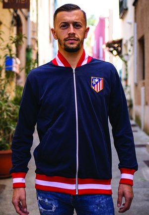 Marine blauwe zip-up jas met rode en witte gestreepte accenten. Bevat een clublogo op de linkerborst en heeft een zachte textuur.