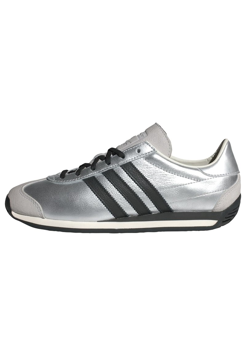 Silver athletic shoe with a smooth leather upper, black three-stripe design, black laces, and a white sole; rounded toe and padded collar.