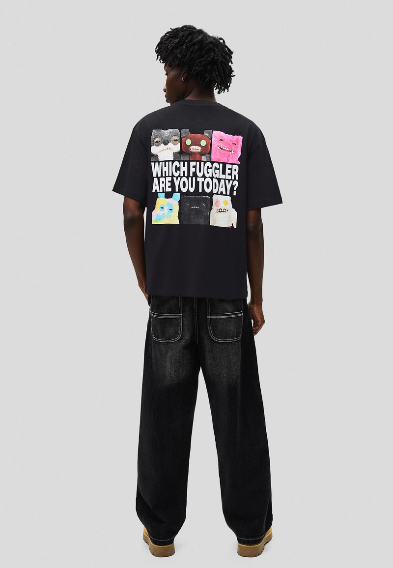 Tricou negru cu imprimeuri colorate cu personaje de desen animat pe spate, cu textul "CARE FUGGLER EȘTI ASTĂZI?" în litere albe îndrăznețe.