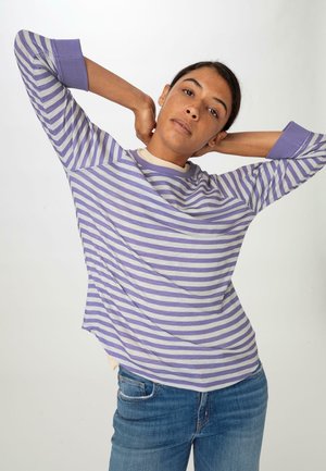 Gestreepte lange mouwen top in lavendel en roomkleur, met een ronde hals en relaxte pasvorm, gecombineerd met blauwe denim jeans.