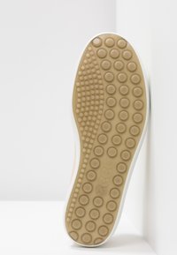 Rubber shoe sole with a rounded design. Color is tan with circular patterns and a white edge. Textured for grip and support.