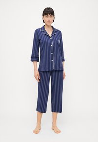Conjunto de pijama de algodão azul-marinho com riscas brancas verticais, apresentando uma camisa com colarinho de mangas três quartos e calças até ao joelho.