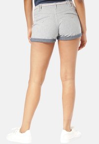 Šedé denimové kraťasy s ohrnutými manžetami, viditelnými zadními kapsami a pruhovaným pasem. Vyznačují se čistým designem a měkkou texturou.