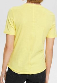 Camicia gialla a maniche corte con collo rotondo e cucitura dritta sul retro. Realizzata in tessuto leggero con una consistenza morbida.