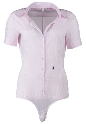 Kvinde går, iført lyserød kortærmet skjorte med knapper, tætsiddende sorte bukser, sorte åbne hæle og holder en beige clutch i venstre hånd.