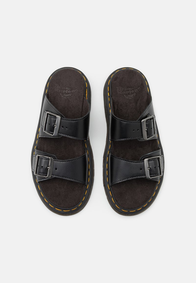 Black sandal with two adjustable straps, featuring silver buckles, suede-like footbed, and textured outsole. Yellow stitching along the edge.