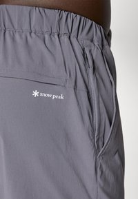 Gray hiking shorts made from lightweight fabric with an elastic waistband, zipper pocket, and subtle logo detail on the side.