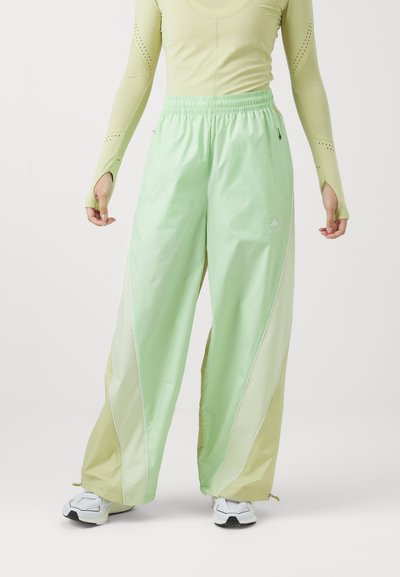 Pantalons vert clair, taille haute, avec une coupe décontractée et une ceinture élastique. Présente des accents blancs et un mélange de textures brillantes et mates.