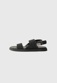 Svart skinnsandaler med to brede stropper og justerbar spenne, med en polstret såle og teksturert fotbed for komfort.