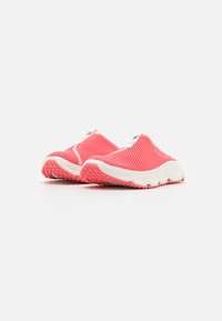Baskets slip-on en mesh rose avec semelles blanches, présentant un motif texturé et une semelle extérieure en caoutchouc rembourrée pour une meilleure adhérence.