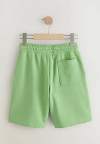 Groene katoenen shorts met een elastische tailleband, voorzien van een achterzak en een gladde, zachte textuur. Gepresenteerd op een houten hanger.