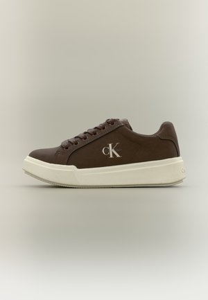 Brązowy sneaker Calvin Klein z białą podeszwą, bocznym napisem logo "CK," i brązowymi sznurówkami, przedstawiony z profilu na jednolitym tle.