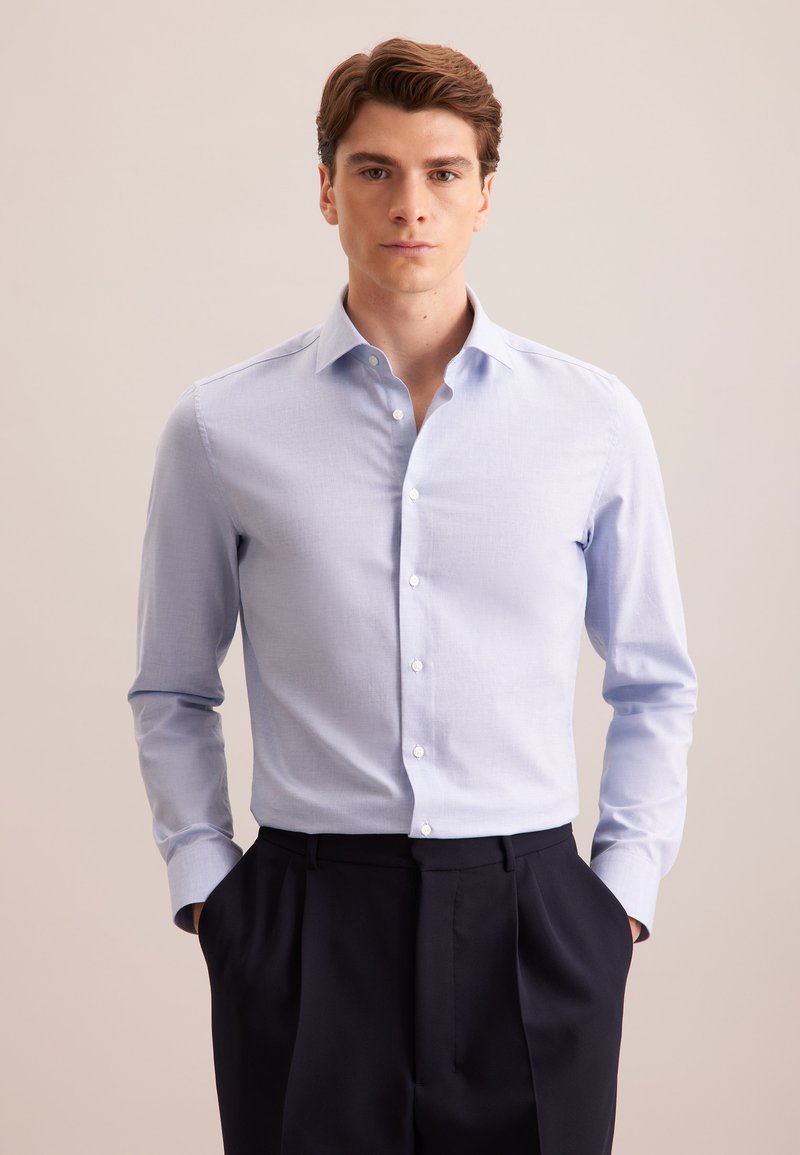 Lichtblauwe overhemd met lange mouwen en een button-down kraag, met witte knopen, gecombineerd met donker op maat gemaakte broek. Gladde textuur, geen patronen.