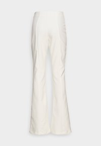 Białe spodnie dzwony, wykonane z gładkiego materiału. Posiadają pionowe szwy i wysoki stan, o czystym, minimalistycznym wzornictwie.