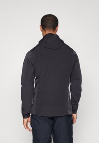 Veste à capuche noire avec une texture lisse, présentant des manches raglan, une capuche ajustable et un logo discret sur le côté gauche.