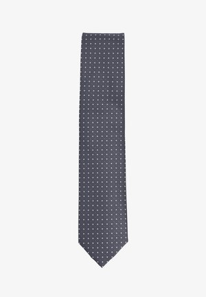 Navy tie with a textured surface, featuring a repeating pattern of small white dots. The tie has a classic slim shape.