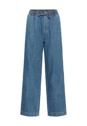 Pantalon large en denim bleu clair avec taille élastique, cordon de serrage et poches latérales. Présente une texture lisse et un design décontracté.
