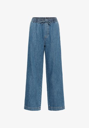 Pantalon large en denim bleu clair avec taille élastique, cordon de serrage et poches latérales. Présente une texture lisse et un design décontracté.