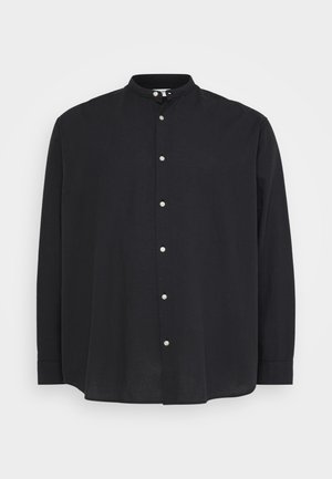 Chemise noire à manches longues avec col bandé et fermeture à bouton. Confectionnée dans un tissu léger, elle présente une coupe ample et une texture subtile.