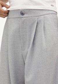 Helle graue, plissierte Hose aus strukturiertem Stoff, mit einem Knopfverschluss und dezenten Nähten nahe dem Bund.