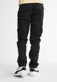 Zwarte cargobroek met een comfortabele pasvorm, voorzien van zijzakken, elastische boorden en een soepele katoenen textuur. gedragen met witte sneakers.