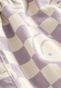 Baumwollstoff mit einem lila- und cremefarbenen Karomuster und abstrakten Wirbeln, der eine weiche Textur und ein glattes Finish aufweist.