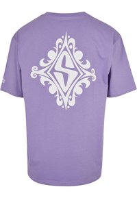 Purple short-sleeve t-shirt featuring a large white ornate design with an 'S' in the center on the back. Made of soft fabric.