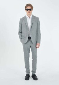 Completo grigio chiaro a righe sottili, design aderente, blazer a un bottone, pantaloni abbinati, abbinato a una camicia bianca e occhiali da sole neri. Scarpe opache.