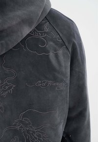 Sudadera gris oscuro con intrincados bordados tonales de nubes y un dragón, con el nombre "Ed Hardy" destacado en la parte posterior.