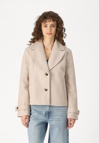 Light beige wool blend jacket with a wide lapel, double-button closure, and side pockets. Features cuffed sleeves and textured fabric.
