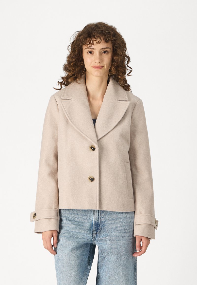 Light beige wool blend jacket with a wide lapel, double-button closure, and side pockets. Features cuffed sleeves and textured fabric.