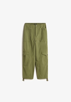 Pantalones cargo color oliva con grandes bolsillos delanteros y laterales con solapa, cierre con botones, presillas para cinturón y cordones ajustables en los bajos.