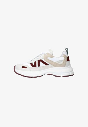 White sneaker with red and beige accents, textured upper, and a thick white sole. Features lace-up design and a heel tab in dark green.