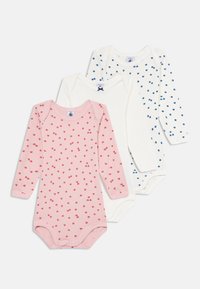 Tre langermede baby-bodyer, to hvite med blå og ensfargede mønstre, en rosa med små røde prikker, lagt flatt på en hvit bakgrunn.