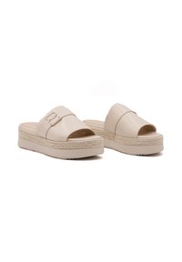 Beige platform slipper sandalen gemaakt van synthetisch materiaal met brede banden en een gestructureerde zool, met een gevlochten accent rond de basis.