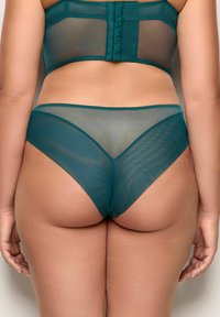 Set di lingerie in rete color teal, caratterizzato da un reggiseno trasparente con pannelli strutturati e un perizoma alto coordinato, che mette in evidenza tagli geometrici e una texture liscia.