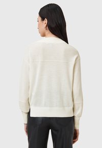 Helle Cremefarbe Sweater aus einem weichen, leichten Strick. Mit lässiger Passform, überschnittenen Schultern und gerippten Bündchen und Saum.