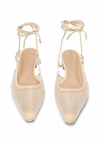 Nude, czółenka na odkrytej pięcie z noskami w kształcie szpica, pokryte fakturowaną koronką, zdobione błyszczącymi detalami i cienkimi paskami na kostce. Gładkie wykończenie wewnętrzne.
