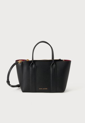 Μαύρη δερμάτινη τσάντα Marc Jacobs με δύο πάνω λαβές, χρυστό φερμουάρ και αποσπώμενο λουρί ώμου, με κόκκινη εσωτερική επένδυση.