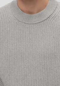 Pull gris clair en tricot avec une texture côtelée et un col rond. Le tissu présente un motif uniforme avec des détails fins.