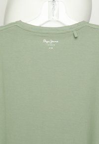 Olivově zelené tričko s kulatým výstřihem, vyrobené z měkké bavlny. Na zadní straně u krku je bíle potisknuté logo "Pepe Jeans London".