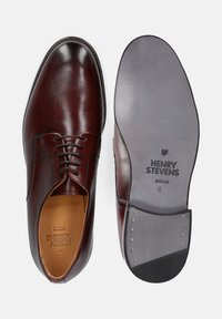 Braune Lederschuhe mit runder Zehenform, Schnürdesign und kontrastierenden Nähten; strukturierte Sohle mit Branding auf der Innensohle und Außensohle.