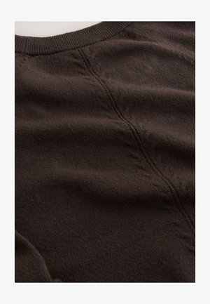 Tumši brūns adīts džemperis ar mīkstu faktūru, apaļu kakla izgriezumu un redzamām adījuma rakstu līnijām gar šuvēm.