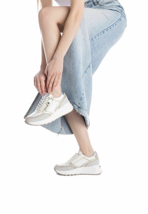 Sneaker bianchi leggeri con accenti grigi, materiali testurizzati e suola chunky. Presentano un design con lacci e un dettaglio con cerniera laterale.